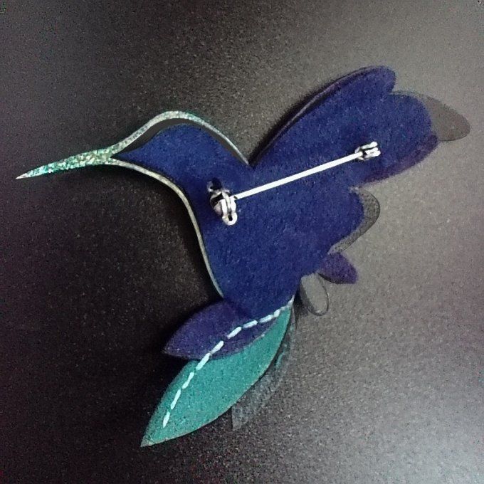 Dos de la broche colibri multicolore, montrant l’attache en laiton fixée sur le cuir.