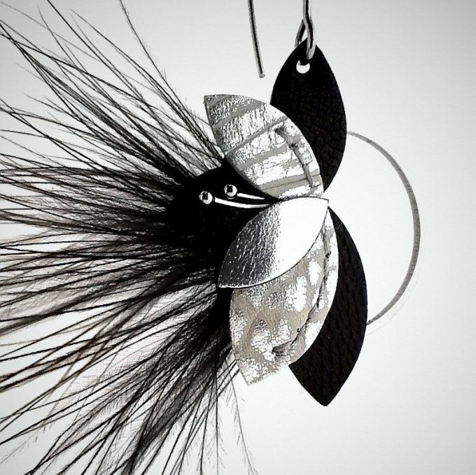 Gros plan sur les détails des boucles d’oreilles Evanescence : fleur en cuir noir et argenté anneaux