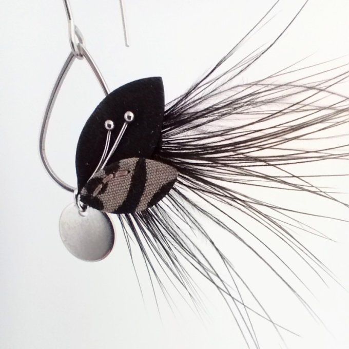 Gros plan sur Sylphide, boucle d'oreille à feuilles de cuir, tissu et plumes cousues à la main.