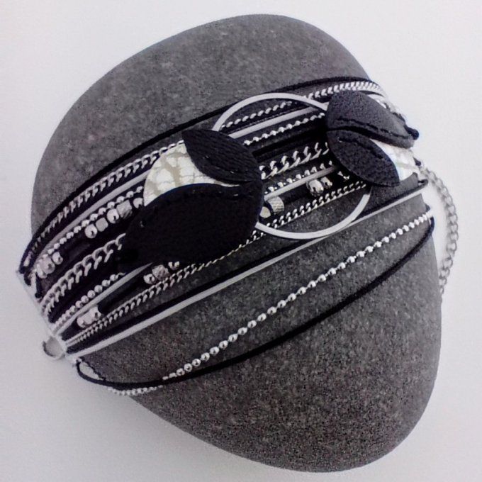 Bracelet multirang Cascade en cuir noir et argenté, avec chaînes et perles inox, posé sur un galet.