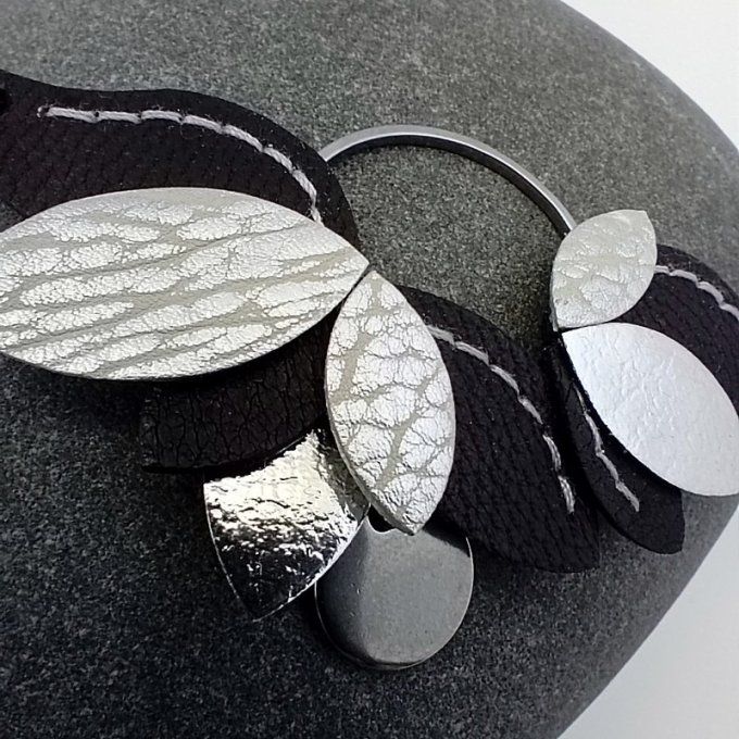 Gros plan des feuilles de cuir noir et argent cousues main du bracelet Nymphéa – finesse du travail