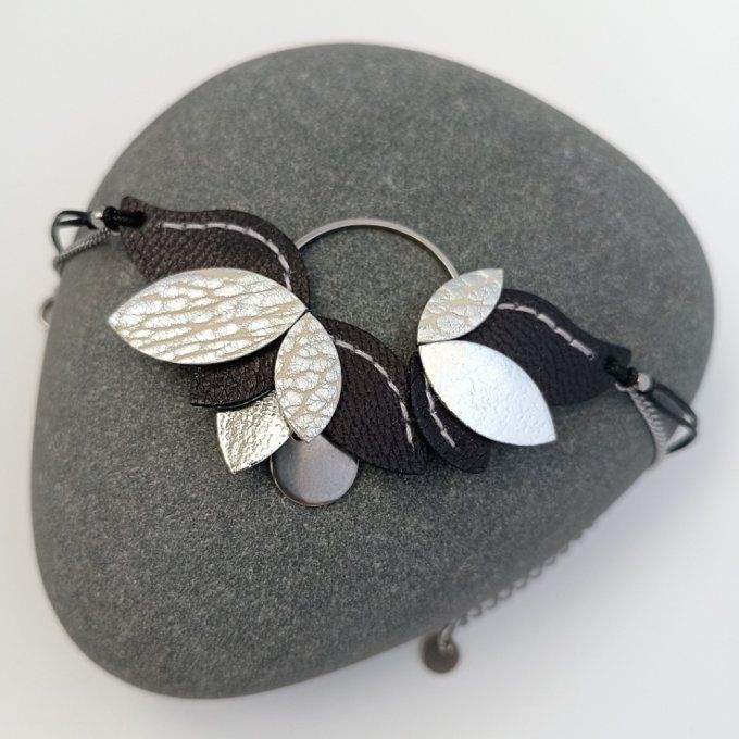 Bracelet Nymphéa, coloris Éclipse posé sur galet gris : feuillage en cuir noir et argent cousu main 