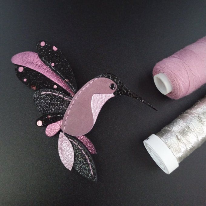 Broche colibri en cuir noir pailleté avec camaïeu de roses, vue de face. Bijou poétique réalisé enti